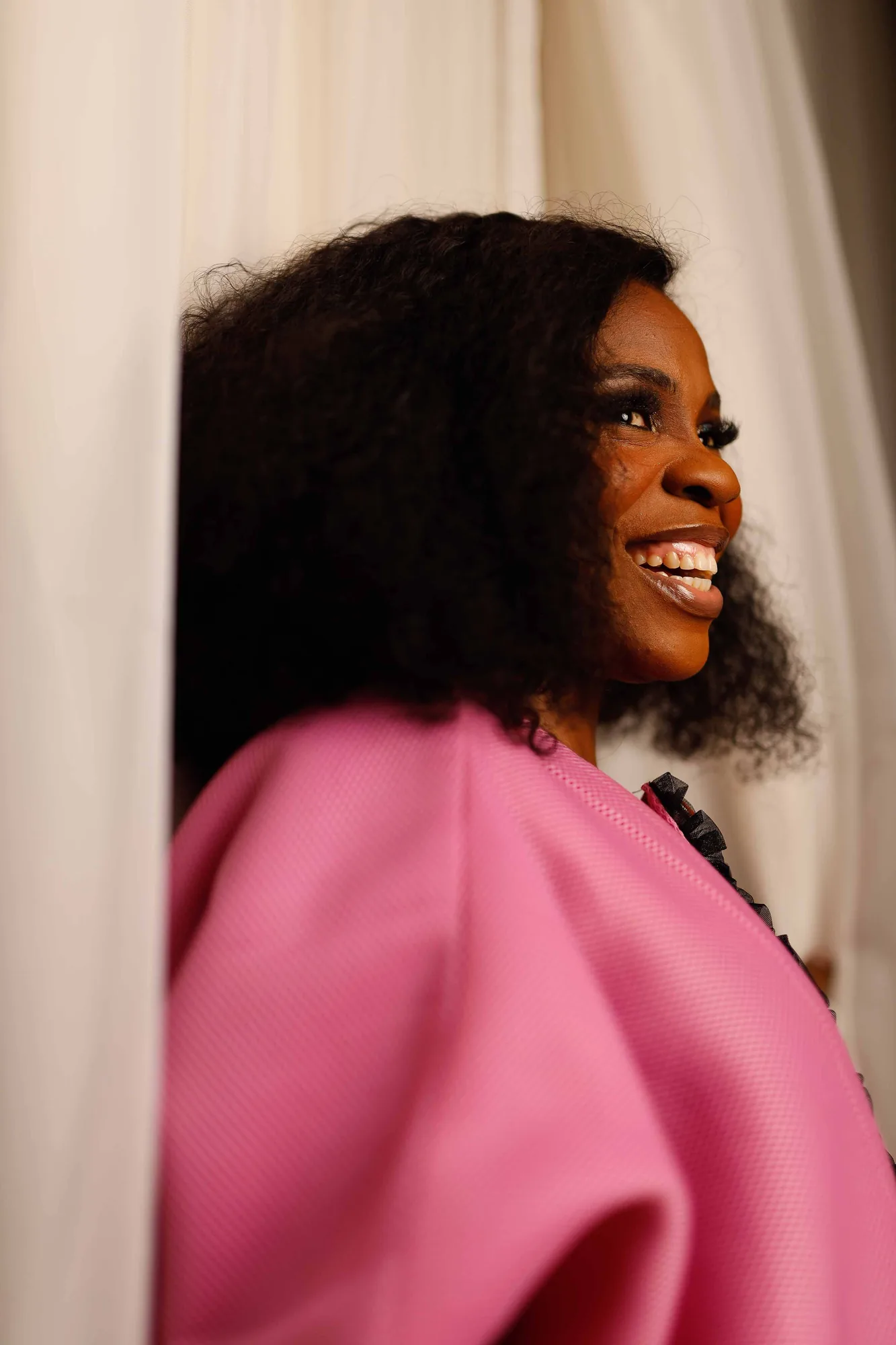 Ebahi laughing, natural hair worn out, in a pink jacket