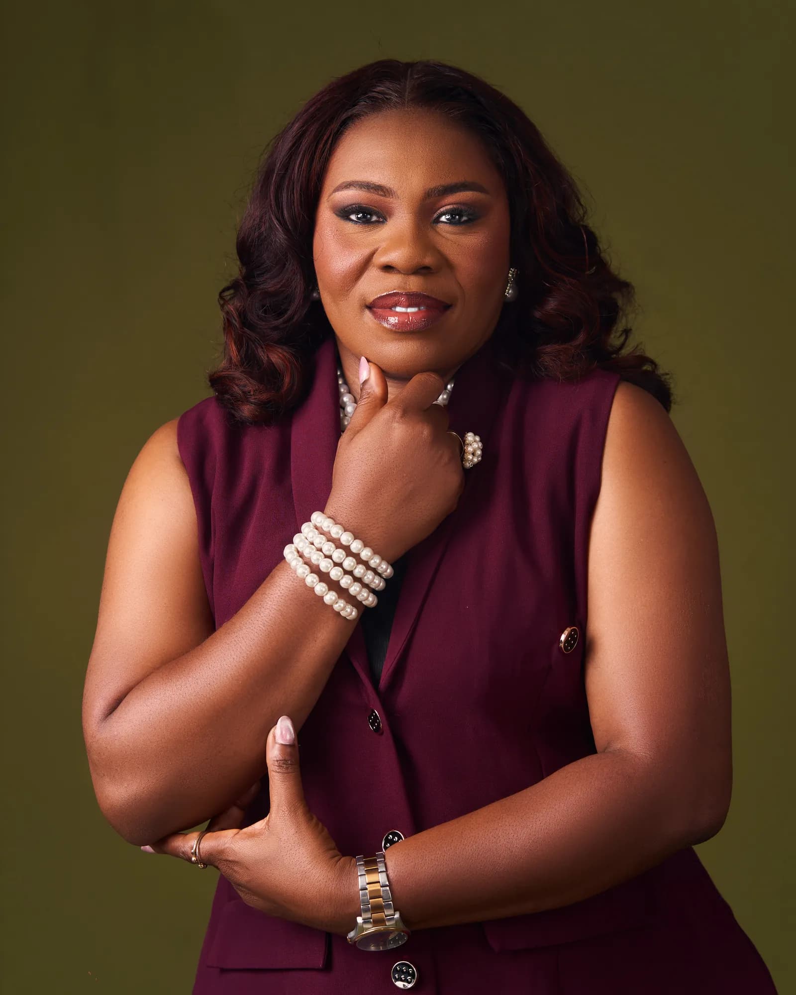 Ebahi in a burgundy waistcoat, hand resting under her chin
